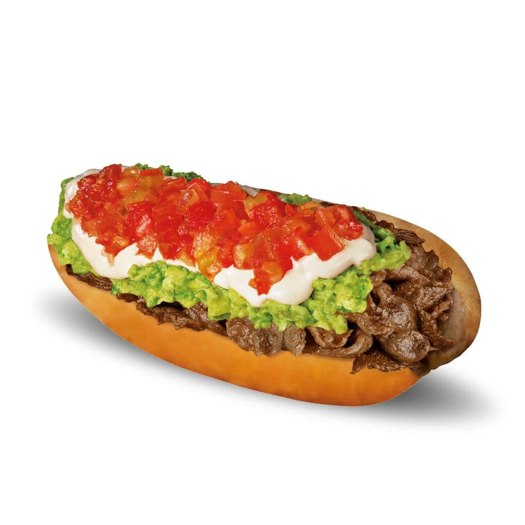 Sándwich de churrasco italiano con carne, palta, mayonesa y tomate sobre un pan suave.